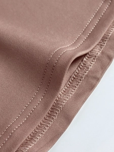 Macro detail of taupe ribbed knit dress showing high-quality stitching and fabric texture