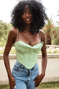 Close-up of light green floral corset top with fishtail hem and blue denim jeans