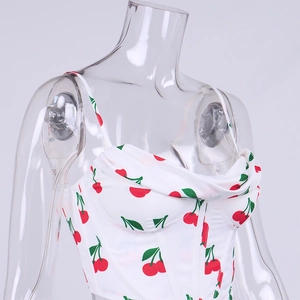 Detail of white camisole top featuring red cherry prints and elegant draped neckline