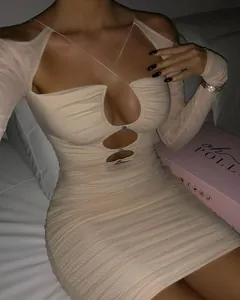 Dettaglio di mini abito beige a maniche lunghe con cut-out e fibbie di strass
