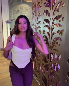 Detail of white corset top with V-hem and high-waist purple pants with side cut-outs