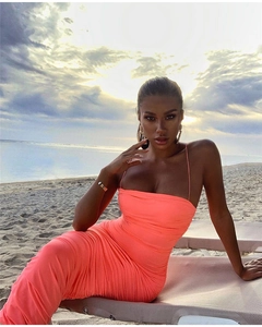 Close-up of vibrant coral pleated camisole dress with spaghetti straps against a sunset beach