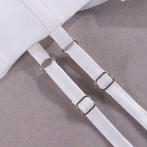 Détail des bretelles réglables avec boucles en métal argenté sur un corset blanc