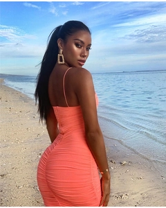Detail of coral ruched bodycon sundress with open back design in a beach setting
