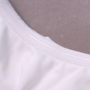 Gros plan sur la texture du tissu en maille blanche et les coutures de qualité de la robe