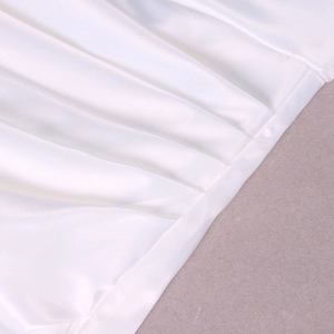 Détail de la robe en satin blanc montrant le tissu plissé et l'élégant éclat perlé