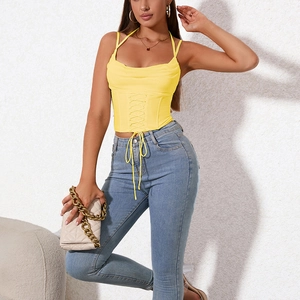 Top caraco corset jaune avec col bénitier et lacets croisés porté avec un jean bleu
