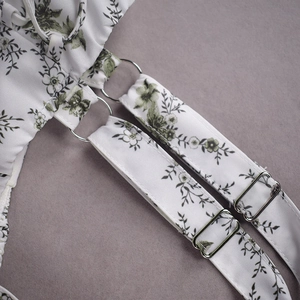Detail eines silbernen Metallrings und verstellbaren Trägers am Sommerkleid mit Blumen