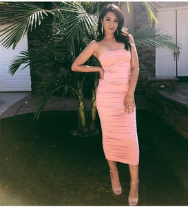 Outdoor shot of a pink ruched midi dress with spaghetti straps on a model in a garden
