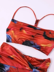 Flat lay of tie-dye two-piece set featuring cropped cami top and ruched skirt in red