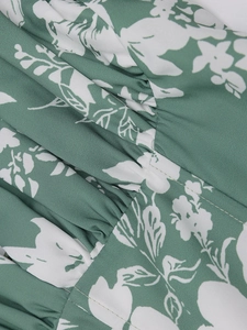 Detail von floralem Stoff mit elastischer Smok-Textur und Nähten eines grünen Sommerkleids