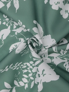 Detailaufnahme von dunkelgrünem Blumenstoff mit weißem Blüten-Silhouette-Muster