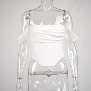 Detail of white corset top featuring ruching across the chest and a pointed hemline