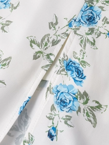 Detailaufnahme von weißem Blumenstoff mit blauen Rosen und Schlitz am Sommer-Maxikleid