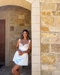 Close-up of white satin mini dress featuring delicate lace trim and dainty bow detail