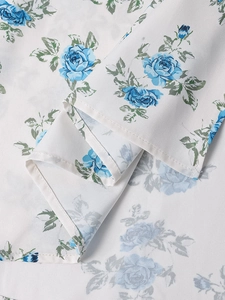 Detail von Blumendruck-Stoff mit blauem Rosenmuster und präziser Naht auf weißem Grund