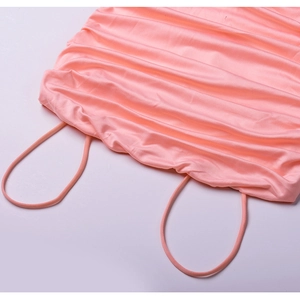 Detail of pink ruched dress featuring fine shoulder straps and glossy soft fabric texture