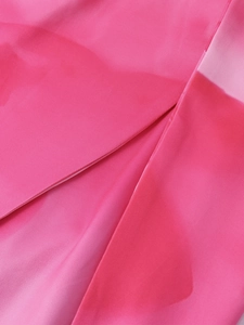 Detailed close-up of rose pink satin fabric with smooth texture and high slit tailoring