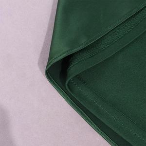 Macro detail of dark green satin dress hem showing fine stitching and mesh lining