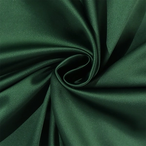 Close-up of emerald green satin dress fabric showing luxurious texture and silky drapes
