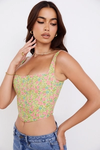 Detail of floral corset top with square neck and pointed hem on a light green fabric