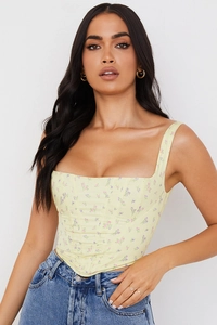 Close-up of floral corset top with square neck and lace-up detail on light yellow fabric