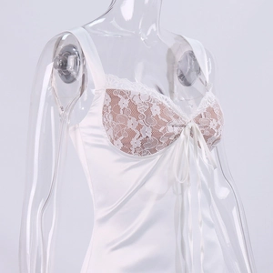 Detail of white satin dress featuring intricate lace trim and a delicate bow decoration
