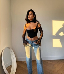 Dettaglio del top a corsetto in mesh trasparente e jeans in denim strappati