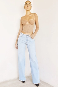 Détail du haut corset à manches en maille et jean taille haute avec franges blanches