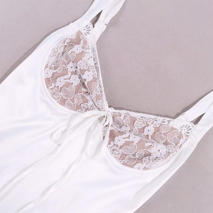 Detailed view of white satin strap dress with floral lace stitching and a small bow