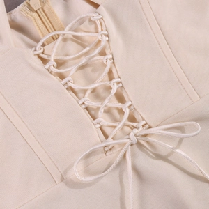 Close-up of the cross lace-up detail and beige twill fabric on the corset mini dress