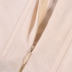 Detail of invisible zipper closure on beige corset dress with textured fabric mesh