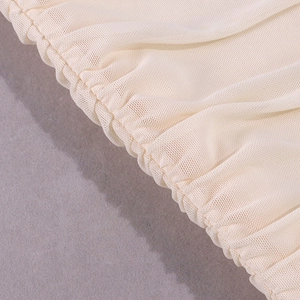 Close-up of beige mesh fabric texture with elastic pleated details and fine netting