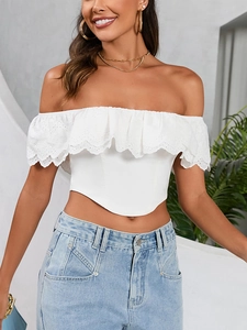 Dettaglio del crop top bianco a spalle scoperte con ricami traforati e orlo a volant
