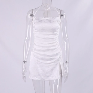 Détail d'une robe courte blanche à licou avec jacquard floral, fronces et fente latérale
