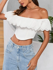 Dettaglio del crop top bianco con spalle scoperte e volant in pizzo ricamato traforato