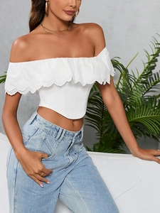 Dettaglio del crop top bianco con rifiniture in pizzo floreale e ricami traforati chic