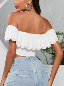 Dettaglio del crop top bianco a spalle scoperte con ricamo e bordi a volant