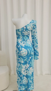 Dettaglio di un abito lungo a fiori azzurro con design monospalla a manica lunga