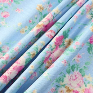 Macro shot of light blue floral fabric with pink roses and twill weave texture