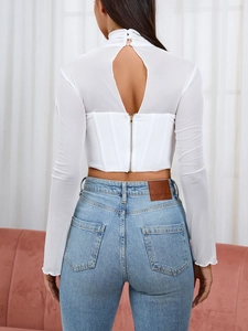 Dettaglio di un top in mesh bianco con apertura a goccia sulla schiena e zip in metallo