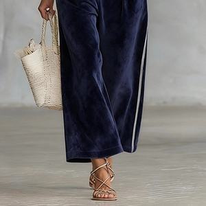 Dettaglio dei pantaloni a gamba larga in velluto blu navy con strisce bianche laterali