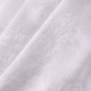 Détail macro du tissu satin jacquard blanc avec motifs floraux et texture élégante