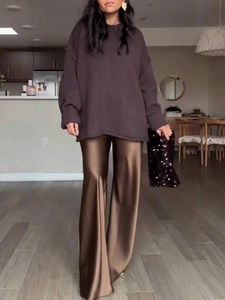 Women's high-waist brown satin wide leg pants paired with an oversized knit sweater