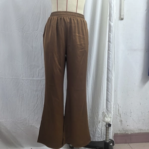 Detailed view of caramel satin wide-leg trousers with elastic high waist and smooth texture