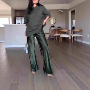 Deep olive green oversized knit sweater paired with glossy satin wide-leg trousers