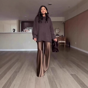 Detail of loose knit sweater with ribbed cuffs and shiny satin wide-leg trousers