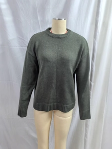 Loose dark green knit sweater with crew neck and ribbed cuffs for a casual winter look