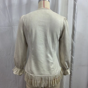 Detail of beige suede top showing tiered fringe hem and ruffled elastic sleeve cuffs