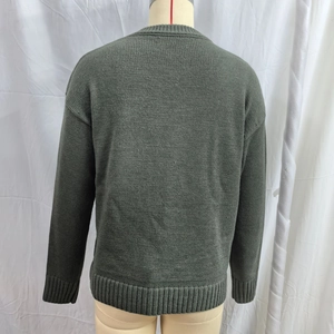 Detail view of the back of a dark green knit sweater with ribbed hem and drop shoulder